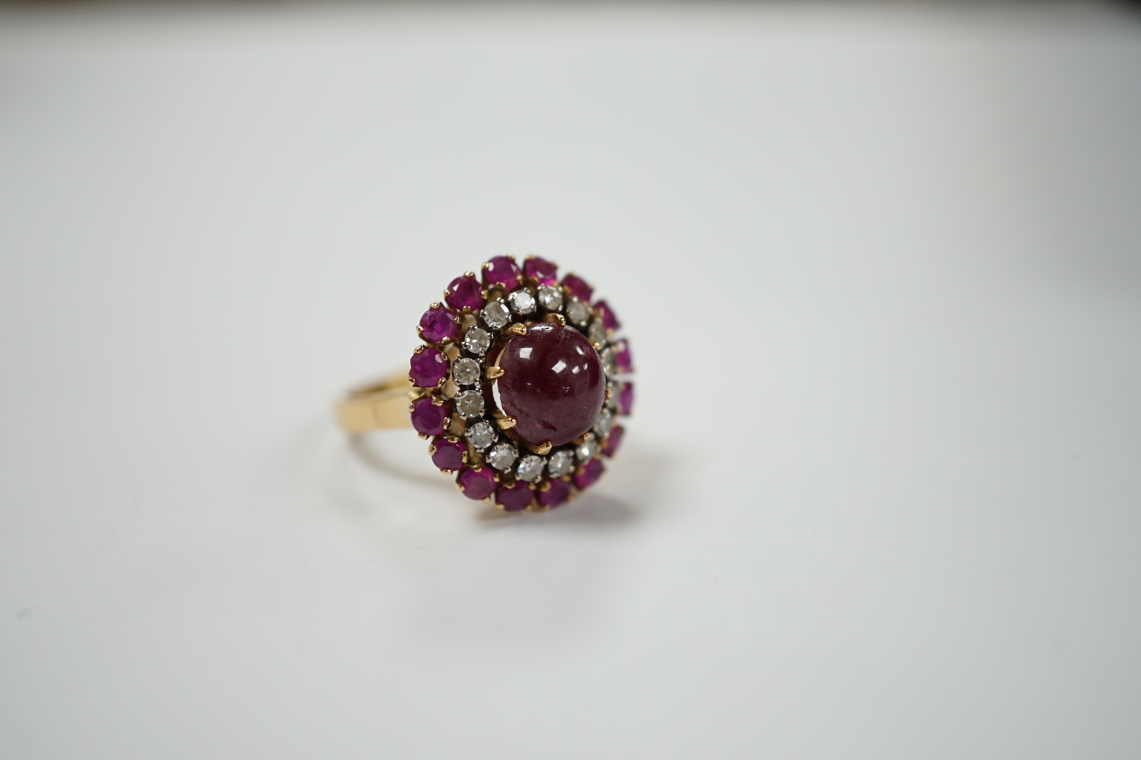 A yellow metal, ruby and diamond set circular cluster dress ring, with central cabochon ruby, size M/N, gross 8.2 grams.